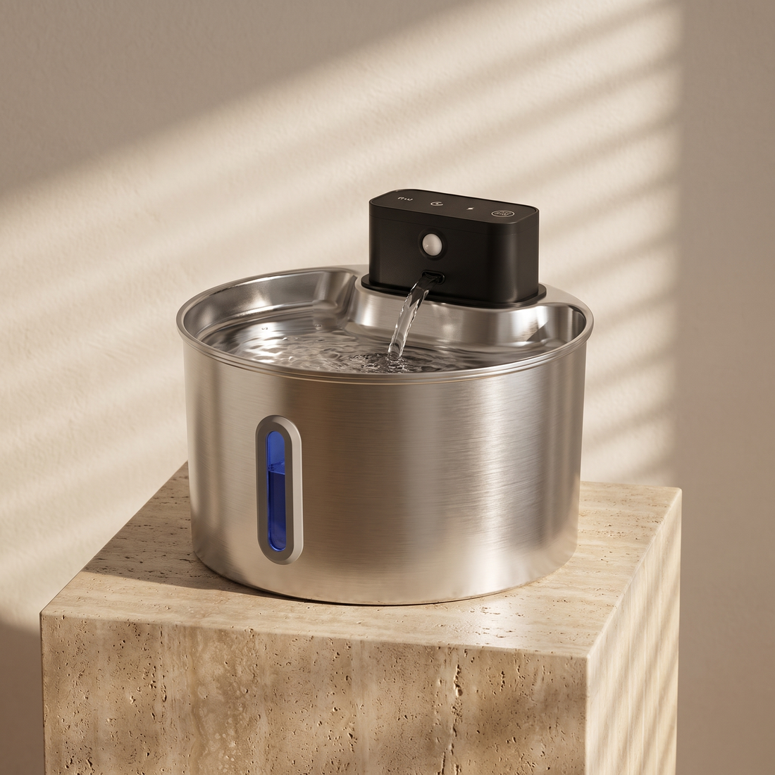 Ars Flow Petite Fountain in brushed stainless steel on a travertine plinth